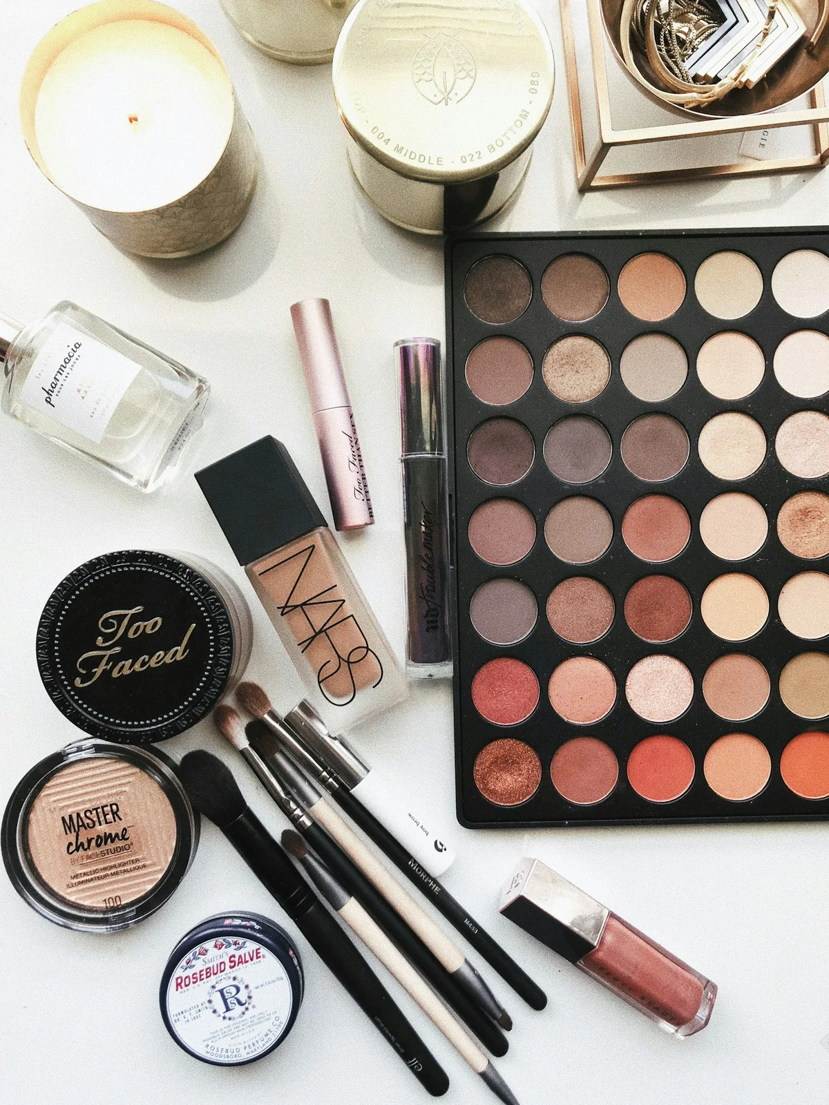 Makeup palette, brushes, and cosmetics in a flat lay